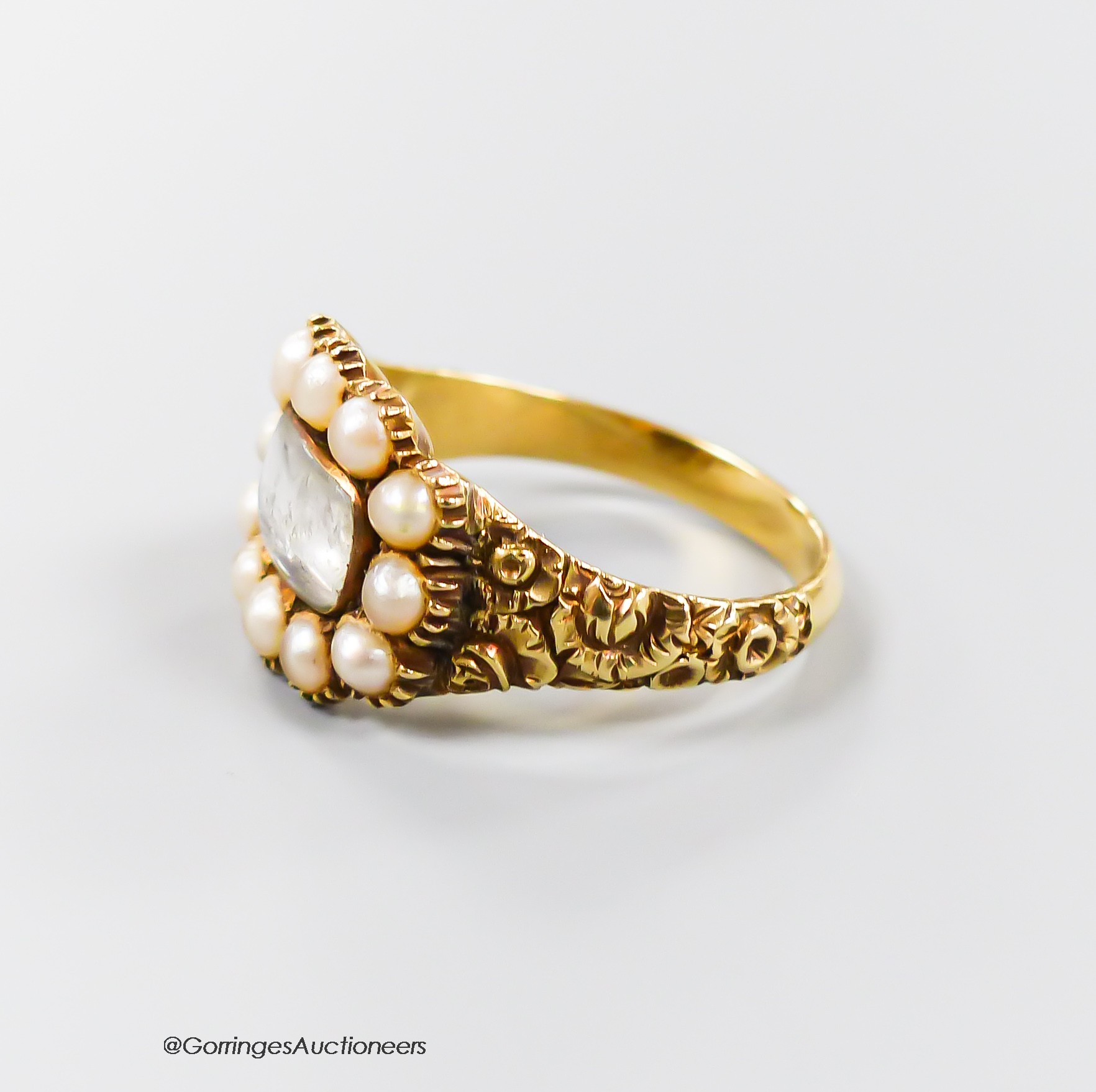 A 19th century yellow metal and split pearl set mourning ring, with plaited hair beneath a glazed panel, size N/O, gross 4.5 grams.